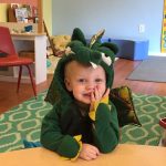 Blonde toddler in a dinosaur costume